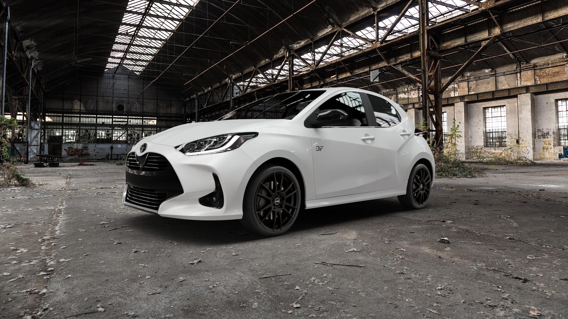 ALUTEC Monstr racing-schwarz Felge mit Reifen in 18Zoll Winterfelge Alufelge auf weissem Mazda 2 (22-) (ZV) (24-) Facelift ⬇️ mit 15mm Tieferlegung ⬇️ Old Industrial Hall_max5000mm_2022 Frontansicht_1