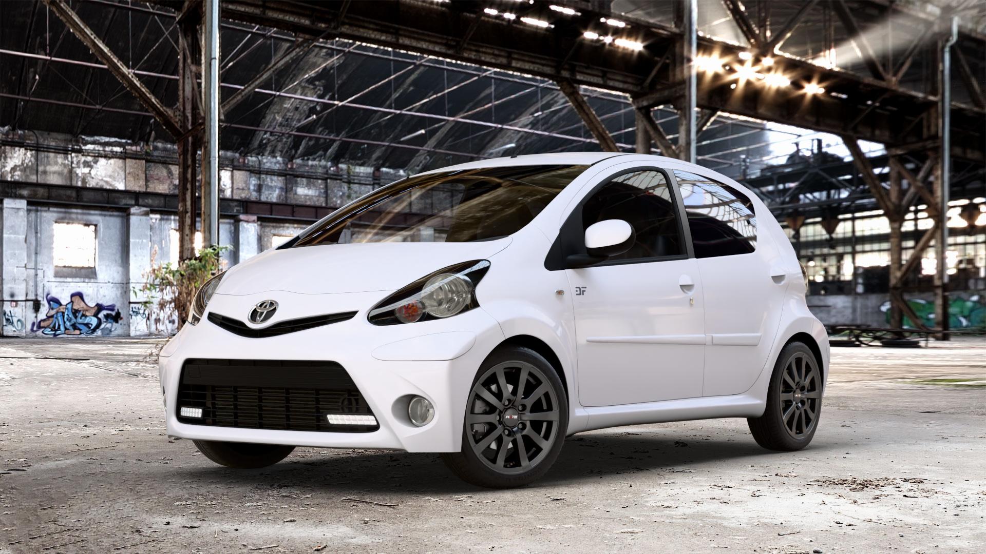 Platin Wheels P 58 matt black Felge mit Reifen schwarz schwarz matt in 15Zoll Winterfelge Alufelge auf weissem Toyota Aygo I ⬇️ mit 15mm Tieferlegung ⬇️ Old Industrial Hall_max_4400mm_2024 Frontansicht_1