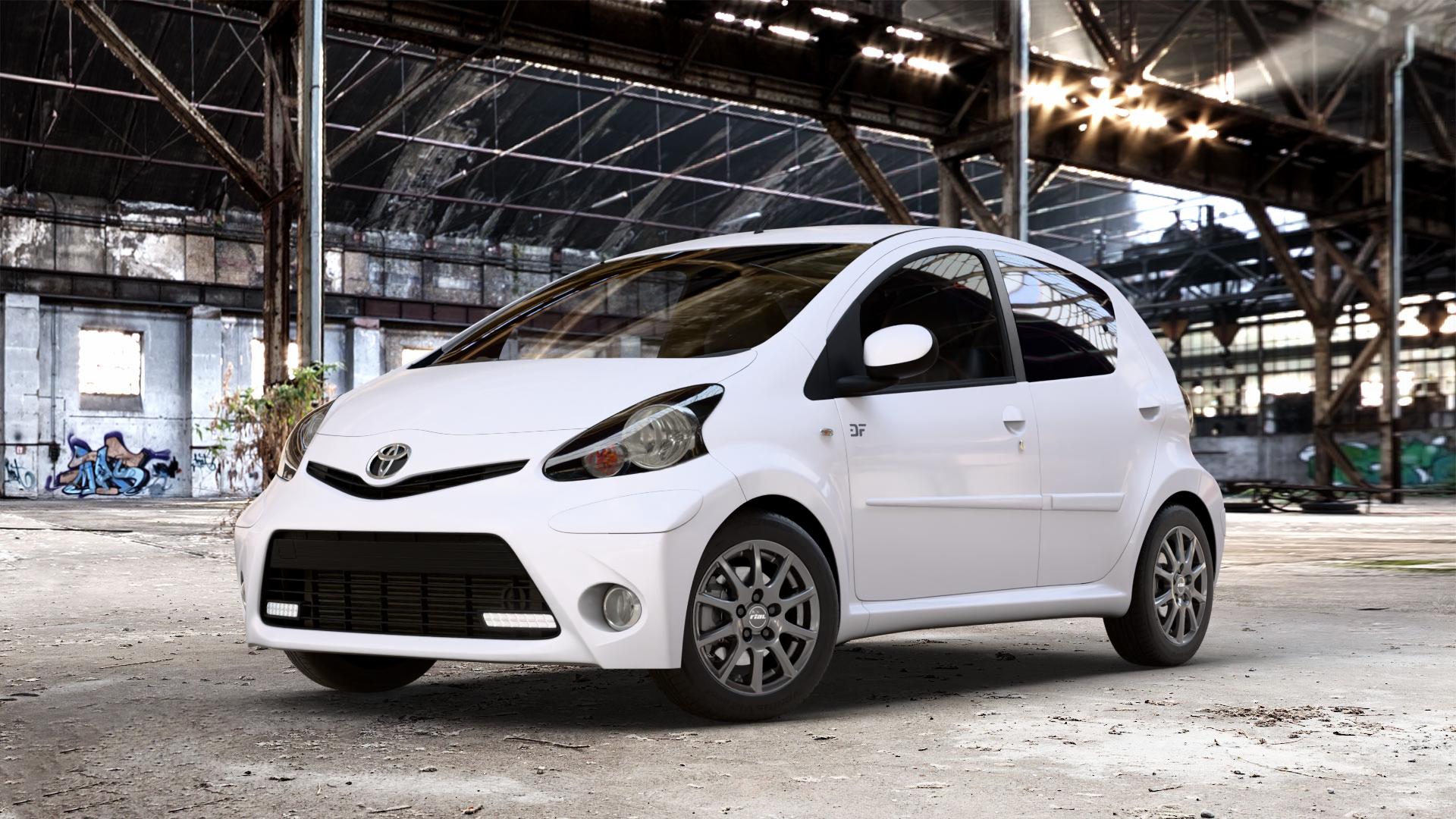 RIAL Milano titanium Felge mit Reifen grau in 14Zoll Winterfelge Alufelge auf weissem Toyota Aygo I ⬇️ mit 15mm Tieferlegung ⬇️ Old Industrial Hall_max_4400mm_2024 Frontansicht_1