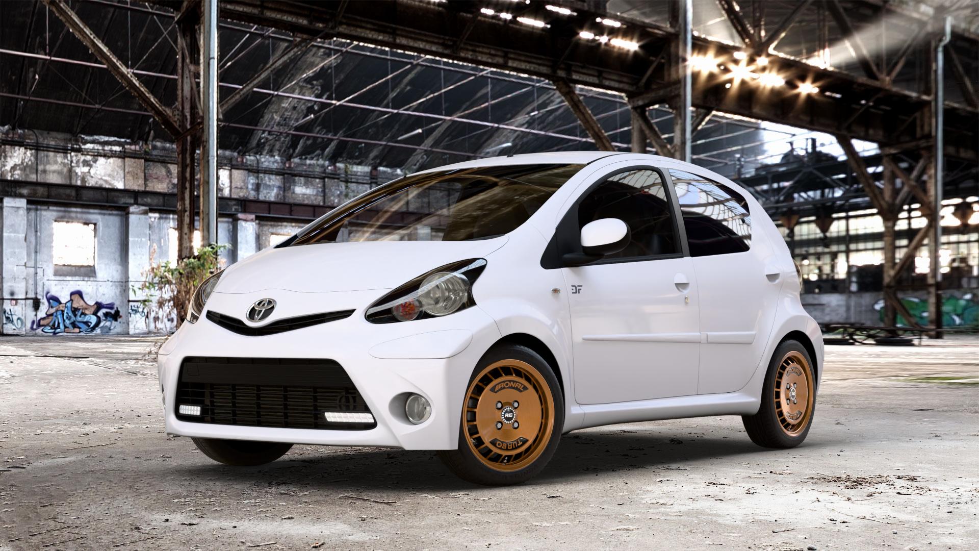 RONAL R10 TURBO COPPER MATT FRONT DIAMOND CUT Felge mit Reifen schwarz bronze in 15Zoll Winterfelge Alufelge auf weissem Toyota Aygo I ⬇️ mit 15mm Tieferlegung ⬇️ Old Industrial Hall_max_4400mm_2024 Frontansicht_1